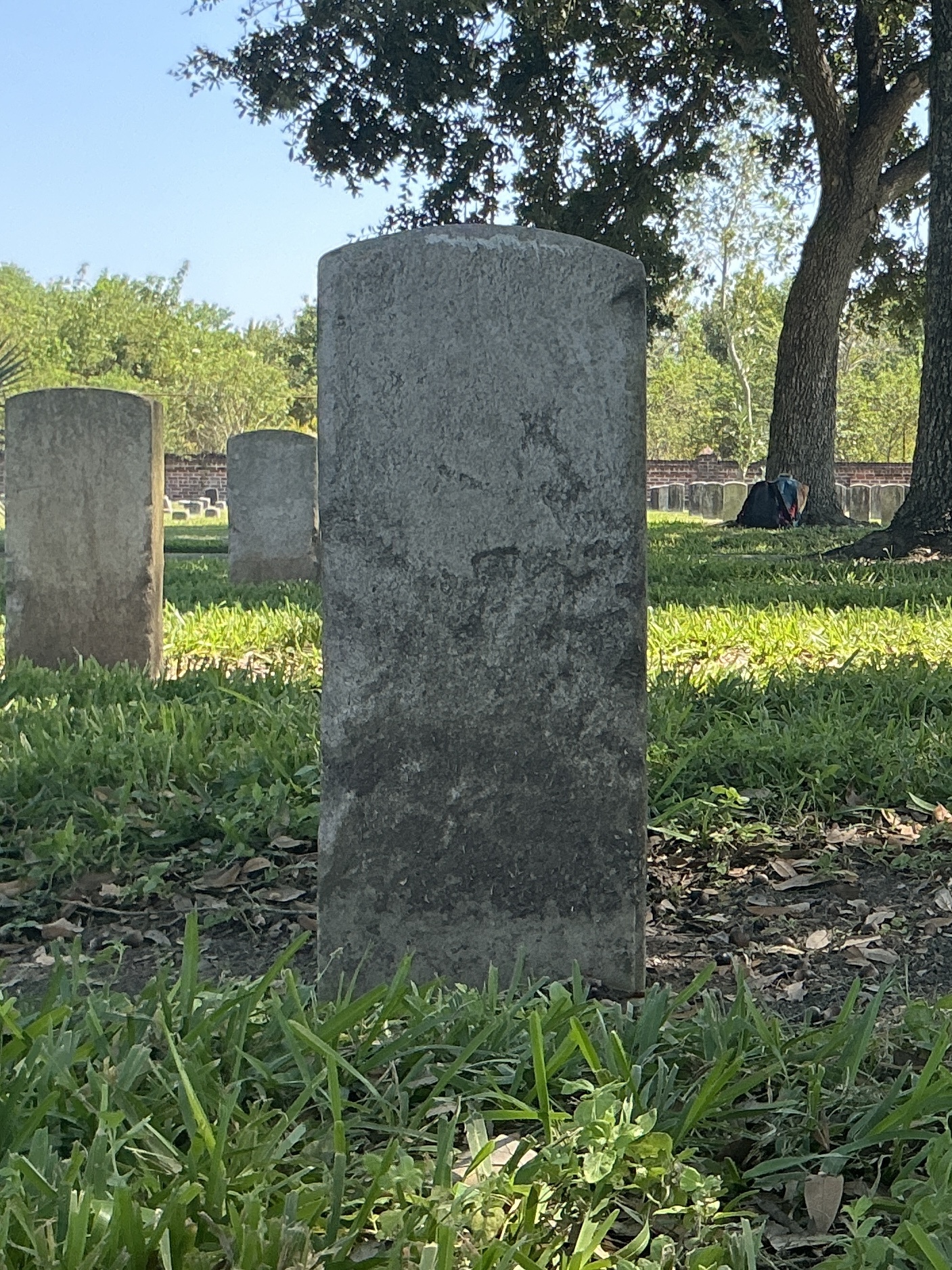 Back of historic upright marble headstone with recessed shield face.