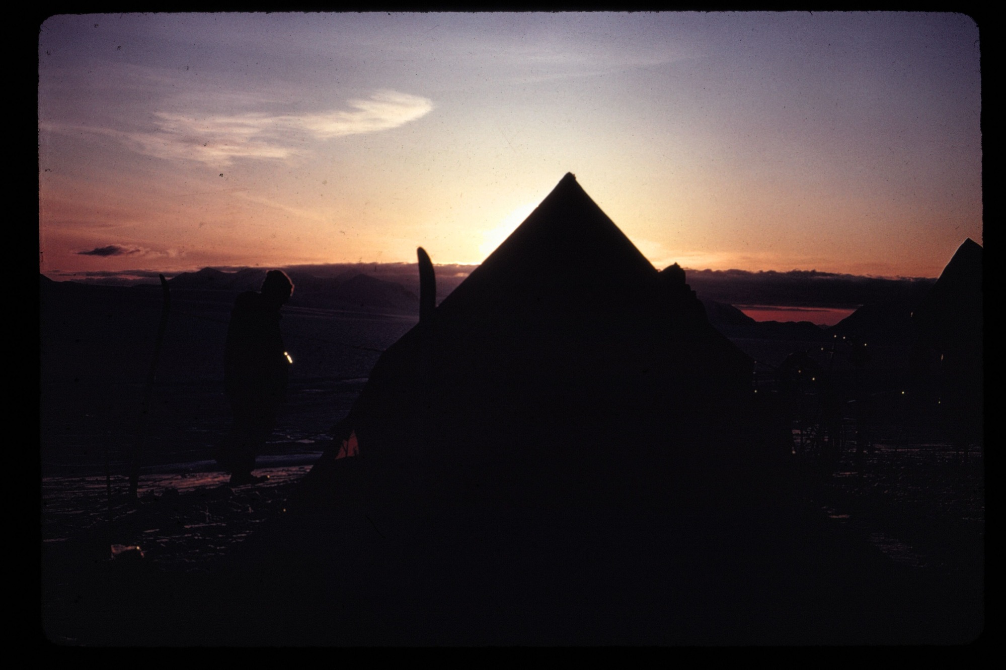 Tent campsite and skis silhouetted against the setting sun over Resurrection Bay during the expedition across the Harding Icefield in April 1968