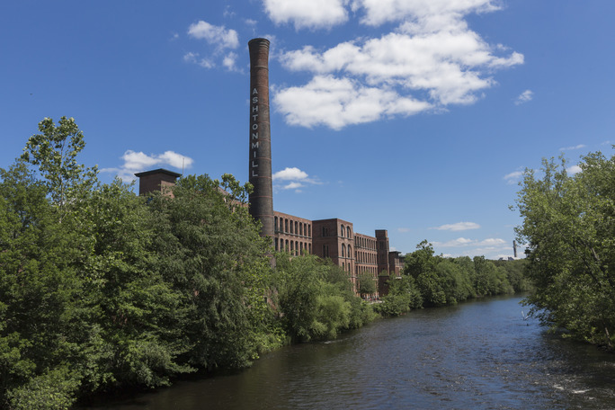 The Blackstone River lined with trees and the Ashton Mill in the background.