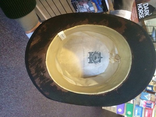 The inside of a black felt hat that is on its side so the inside can be seen. 