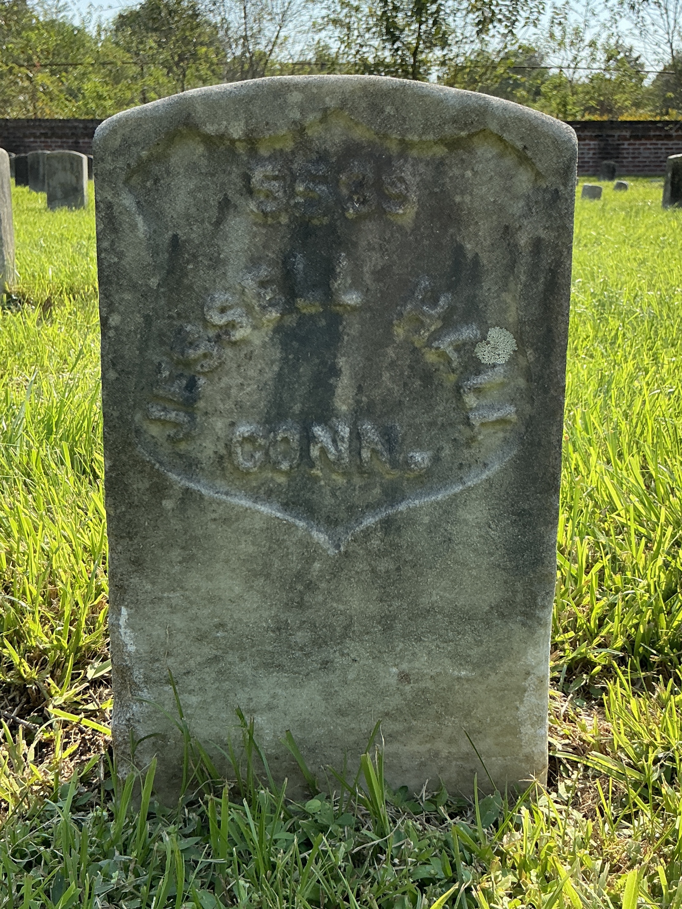 Front of historic upright marble headstone with recessed shield face.