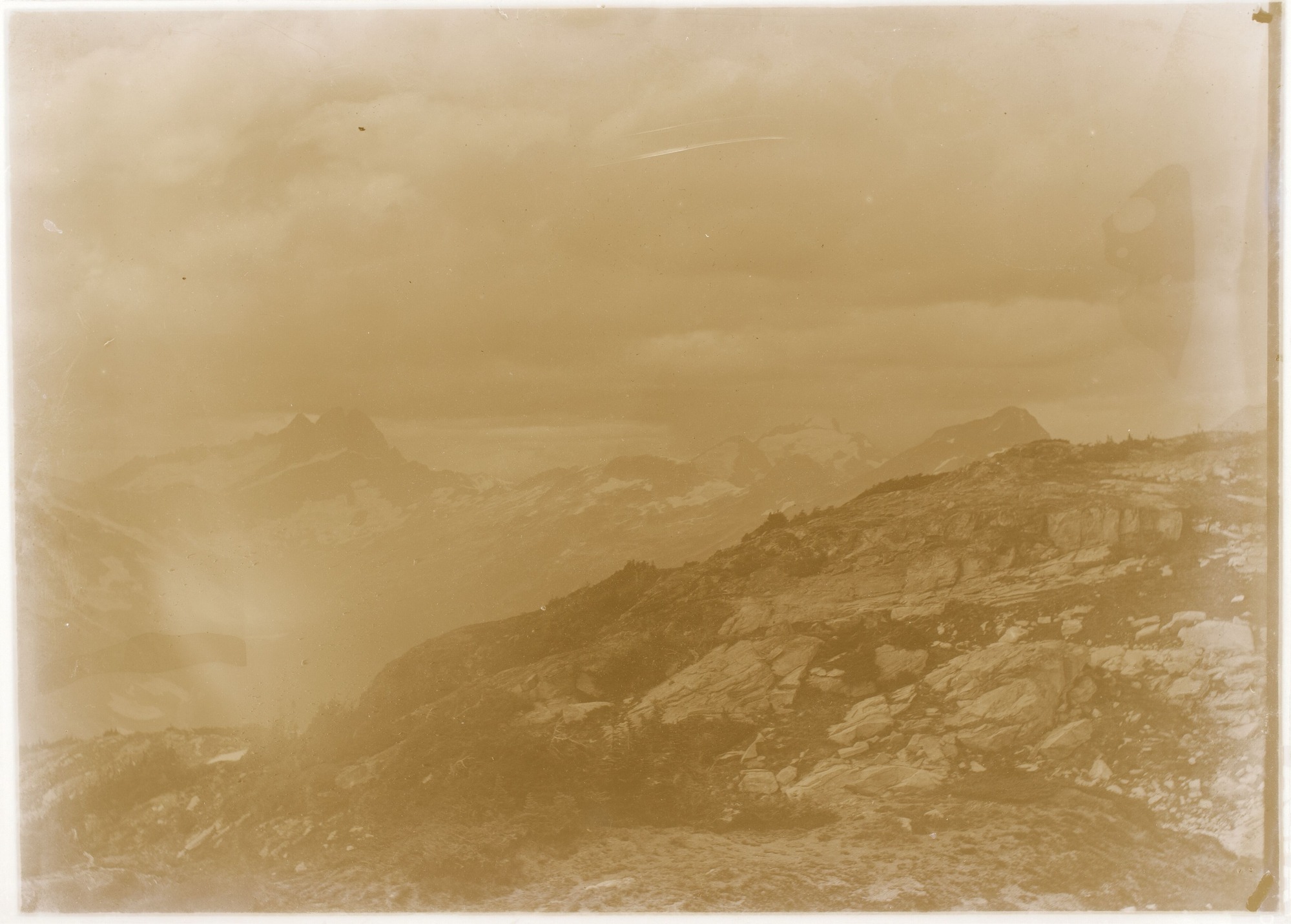 Rocky mountain top with mountain peaks in the background.
