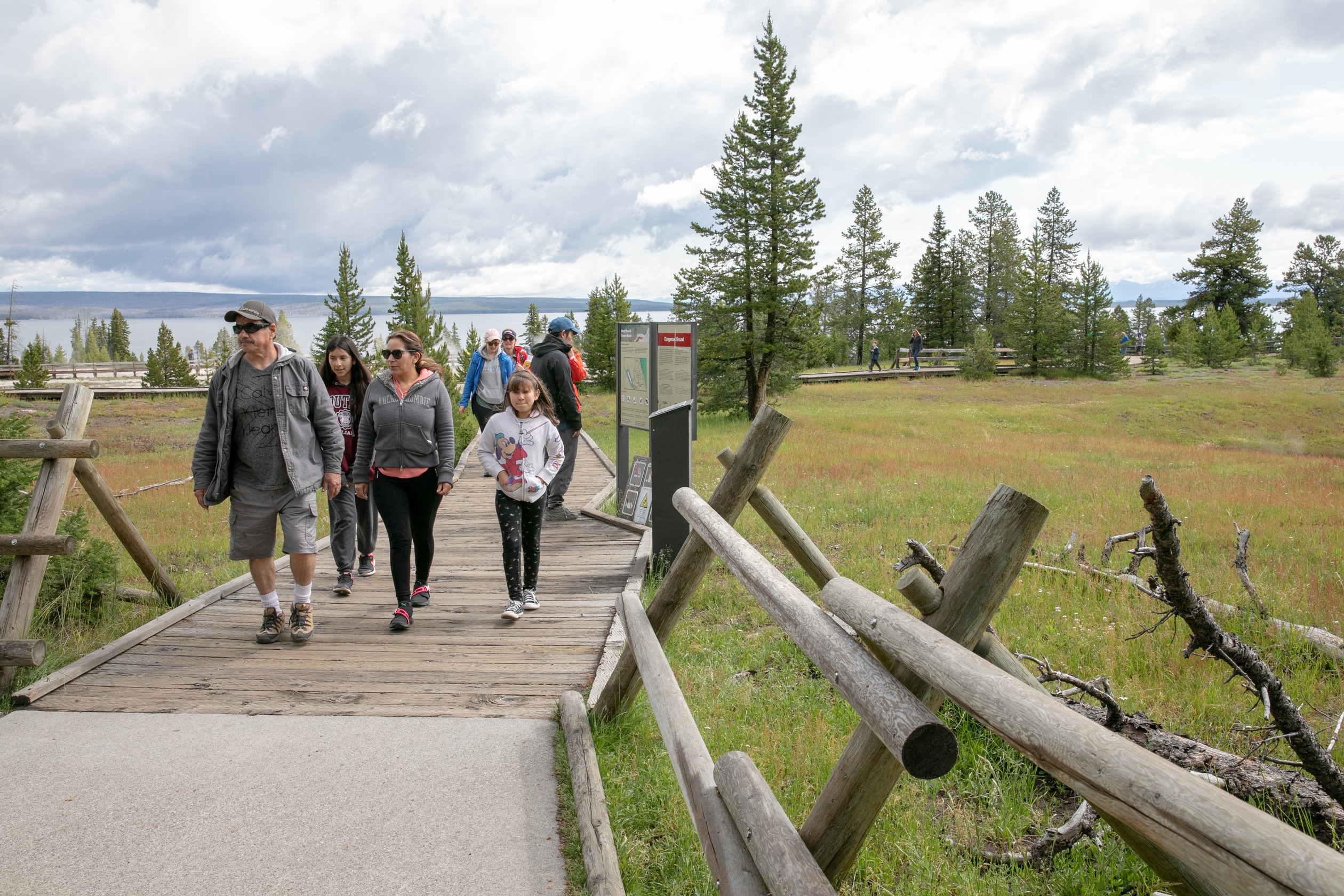 People leave the geyser basin on a boardwalk.