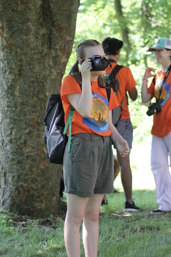 President's Park student volunteer, Abby Bills, stands taking a photo with a camera.
