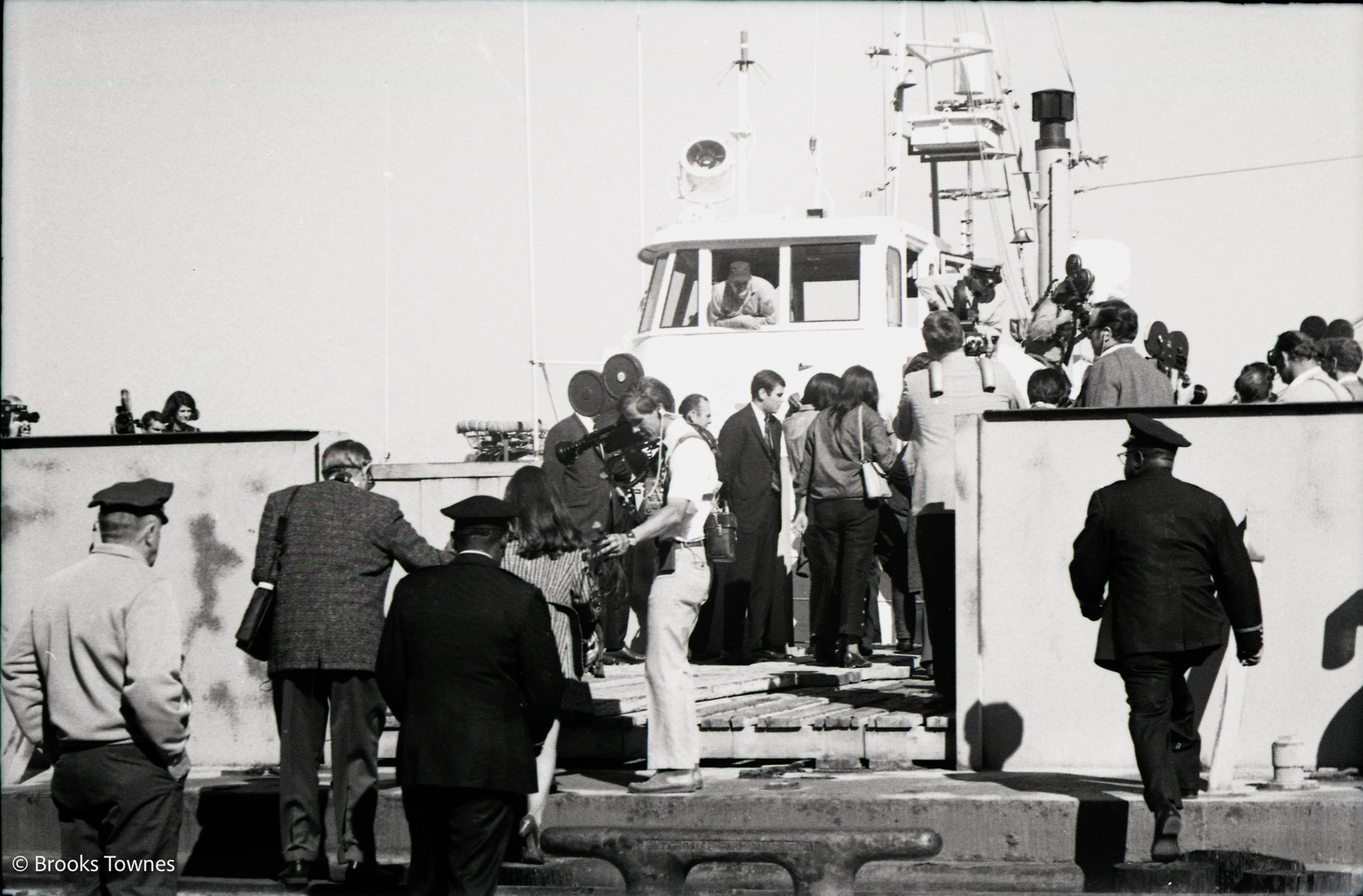 A crowd of cameramen and reporters board a barge 