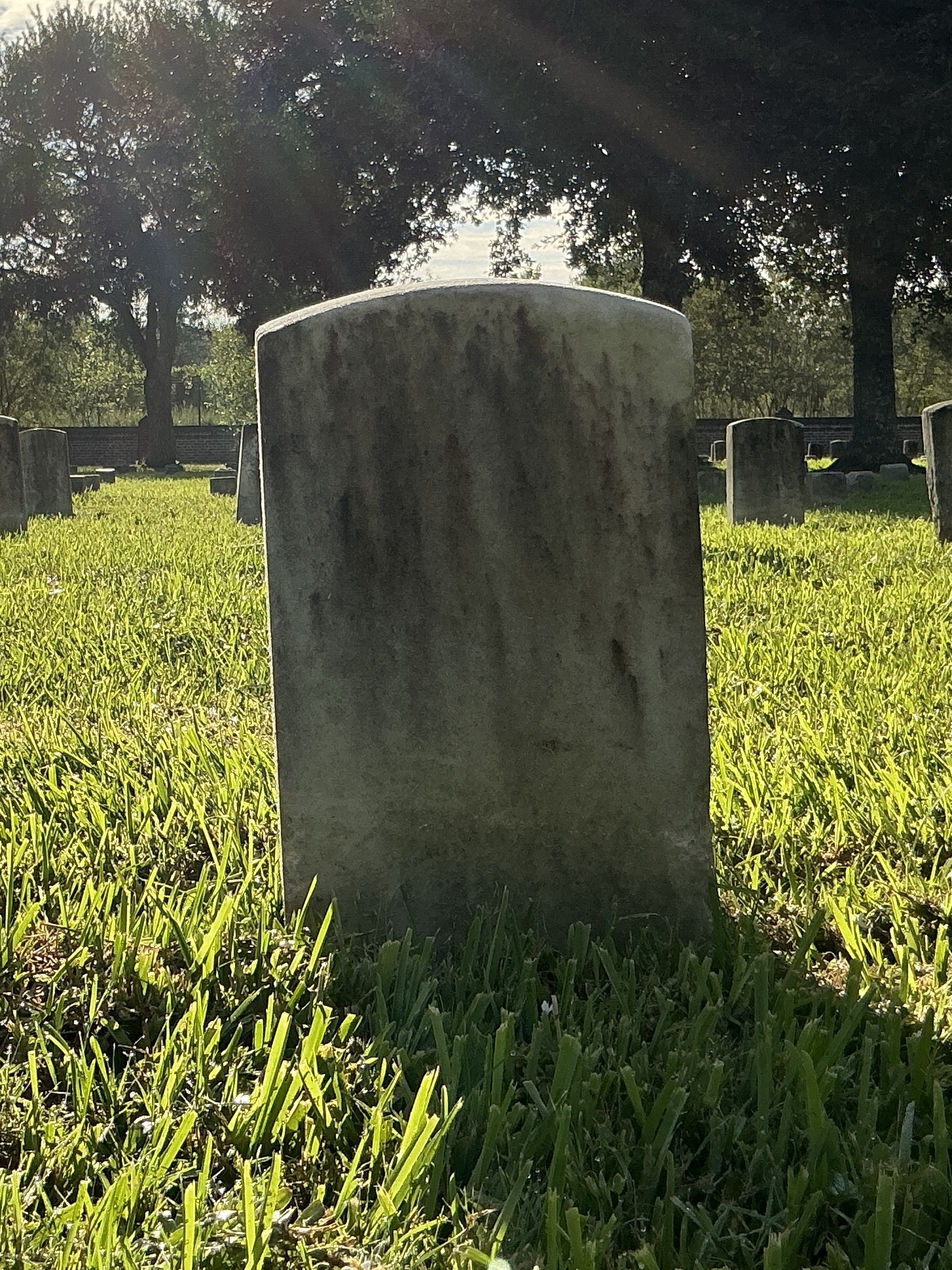 Back of historic upright marble headstone with recessed shield face.