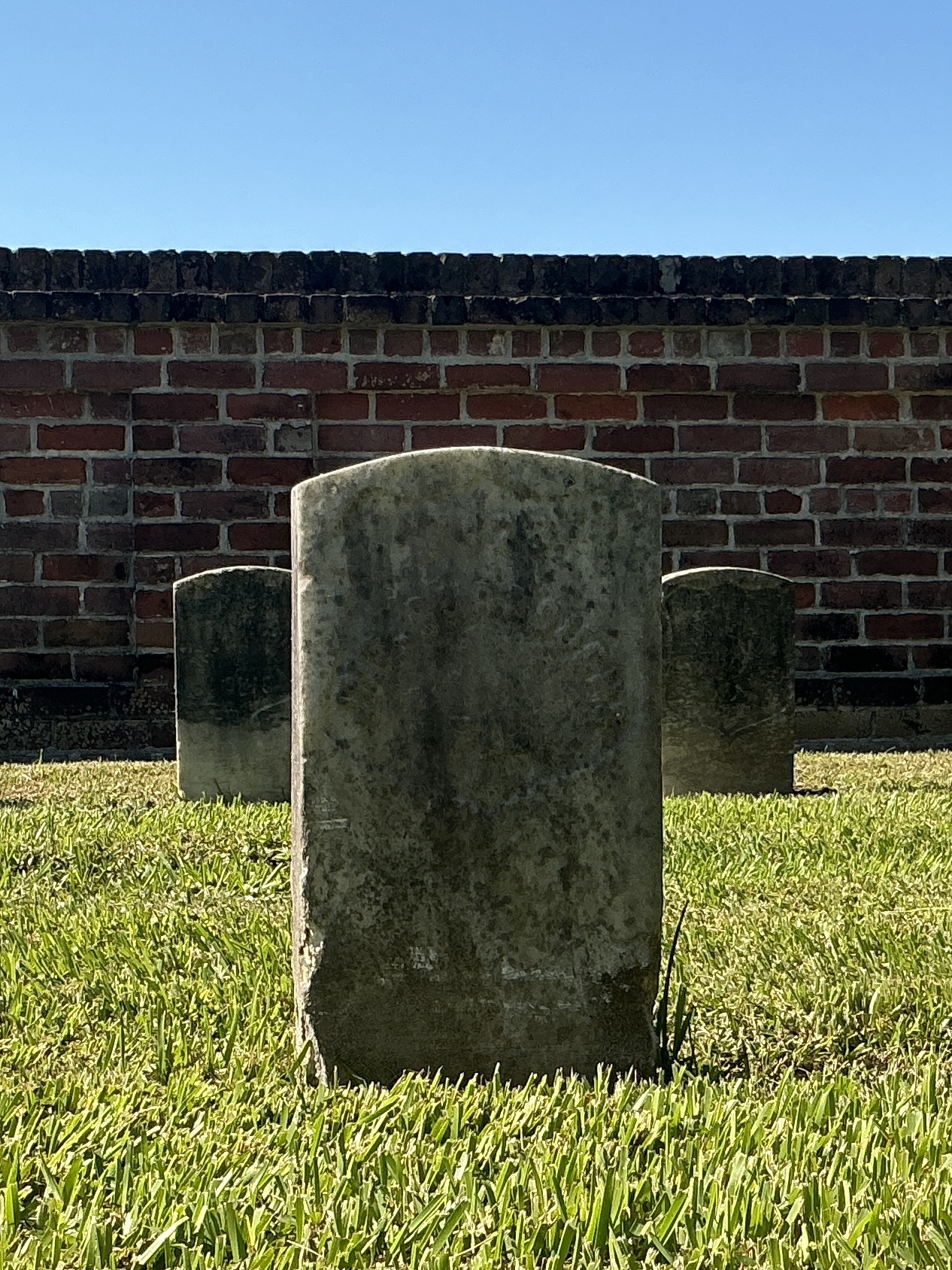 Front of historic upright marble headstone with recessed shield face.
