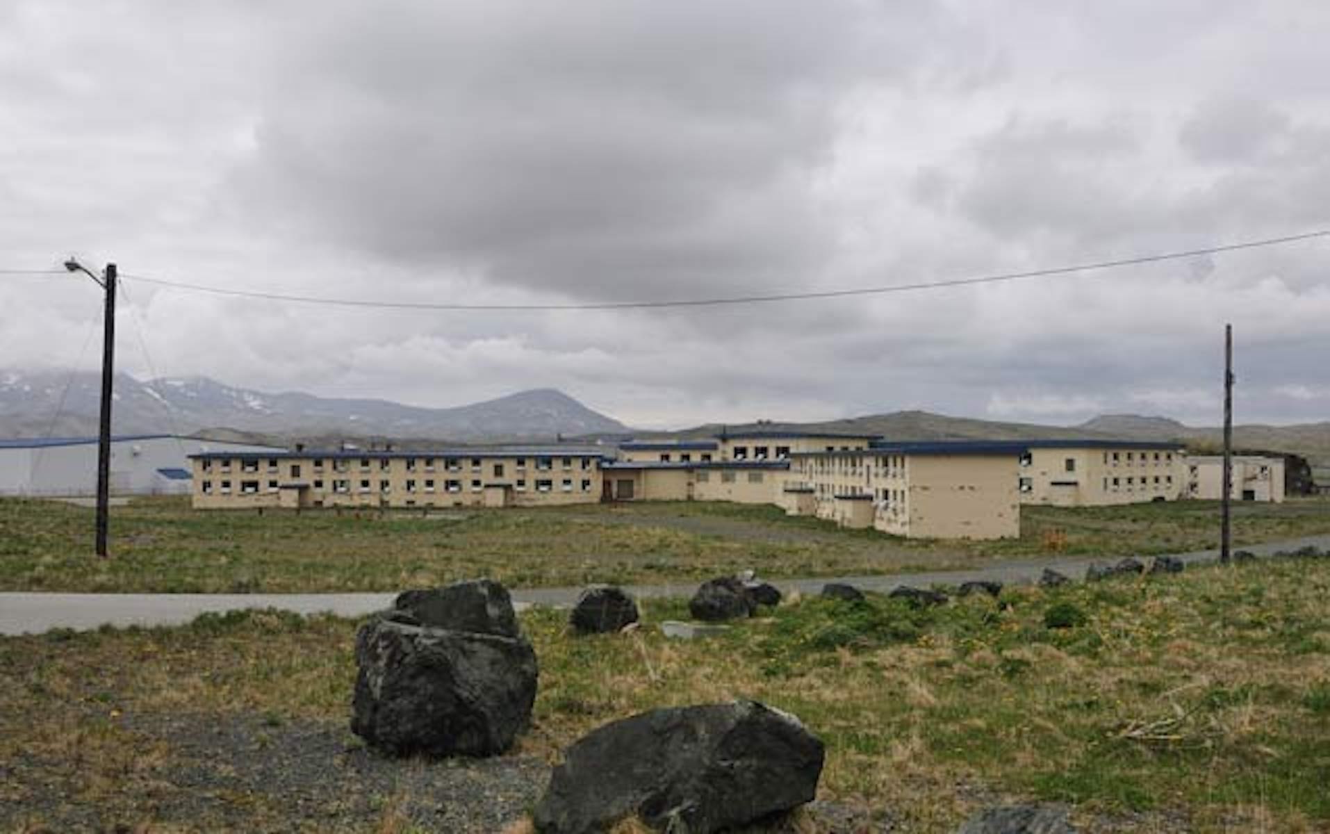 A sprawling beige colored, three story building surrounded by tundra. Mountains are on the horizon.