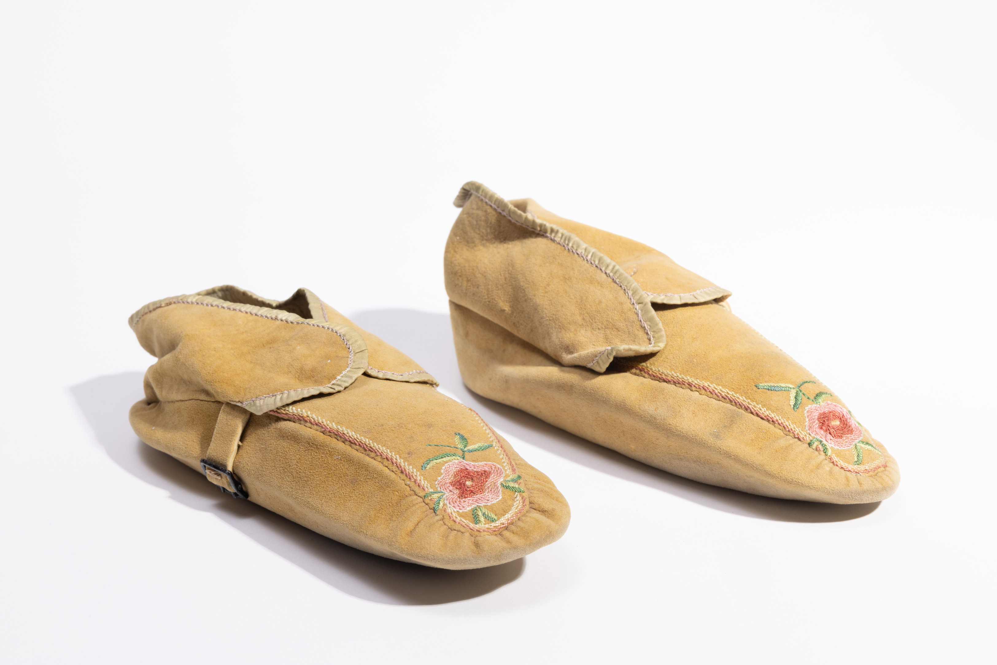 Pair of yellow moccasins with embroidered flower decoration on the toes.