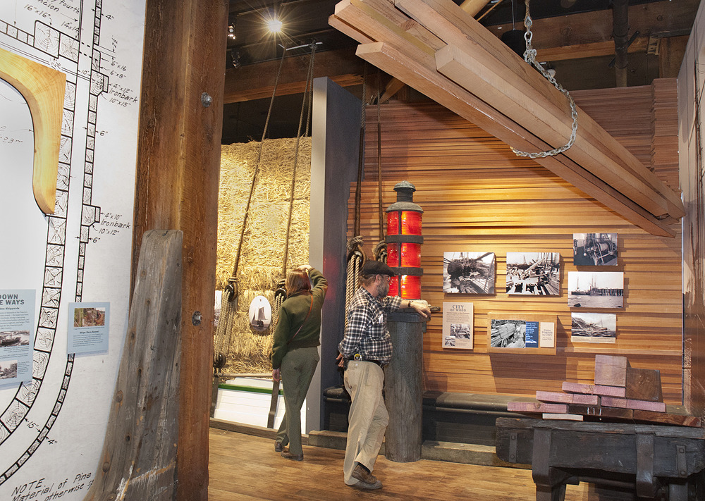 Two people looking at a section of the exhibit about lumber and shipbuilding.