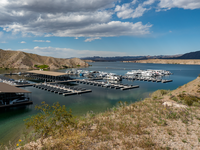 looking down on marina, desert hills and cloudy sky in distance, desert foliage covers sandy hill in foreground