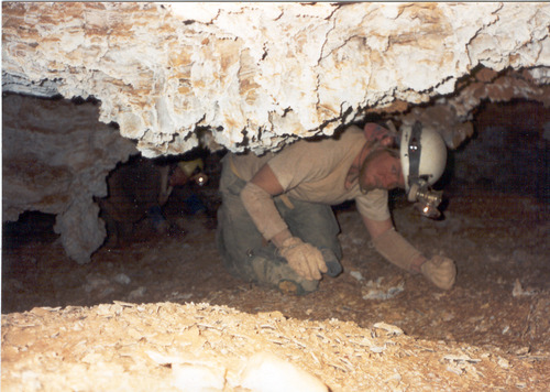 Caver crawling under a low rock ceiling