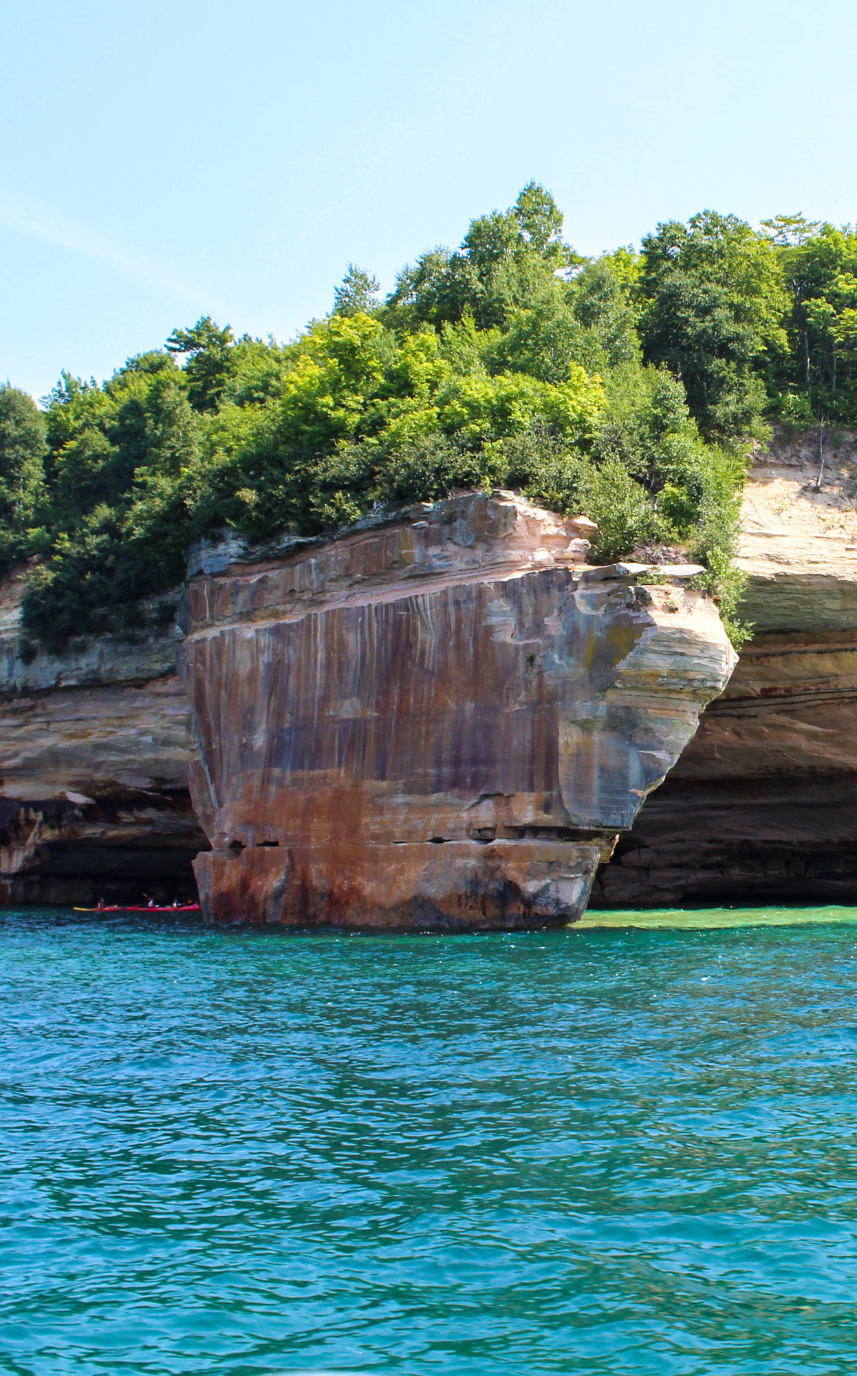 Kayakers passing in between tall rocks in and along a lake