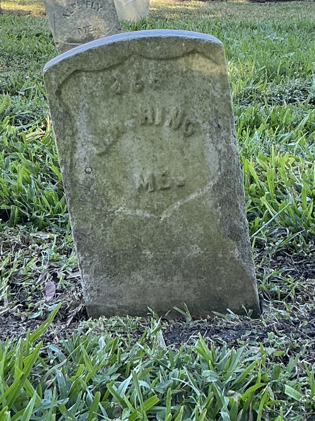 Front of historic upright marble headstone with recessed shield face.