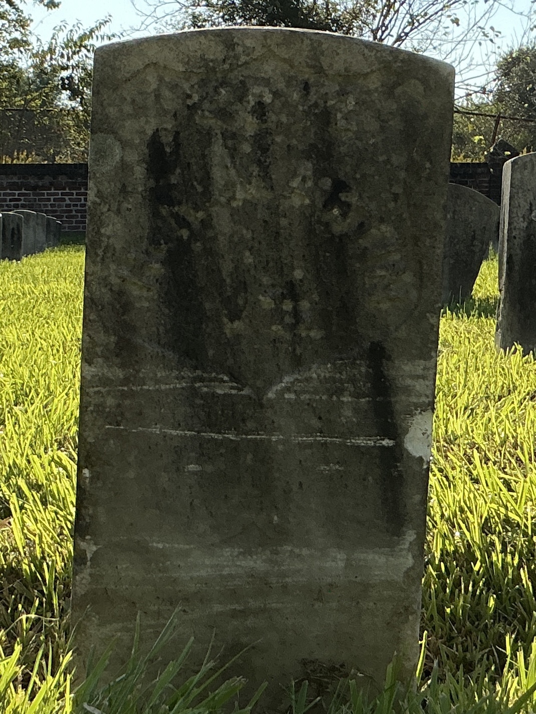 Front of historic upright marble headstone with recessed shield face.