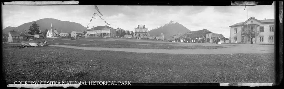 People gathered on the parade grounds near decorated buildings.