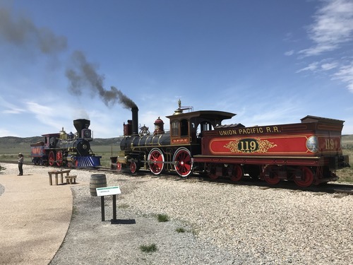 A Ranger stands in front of two steam locomotives delievering a program. 