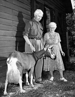 Man and Woman standing next to a goat