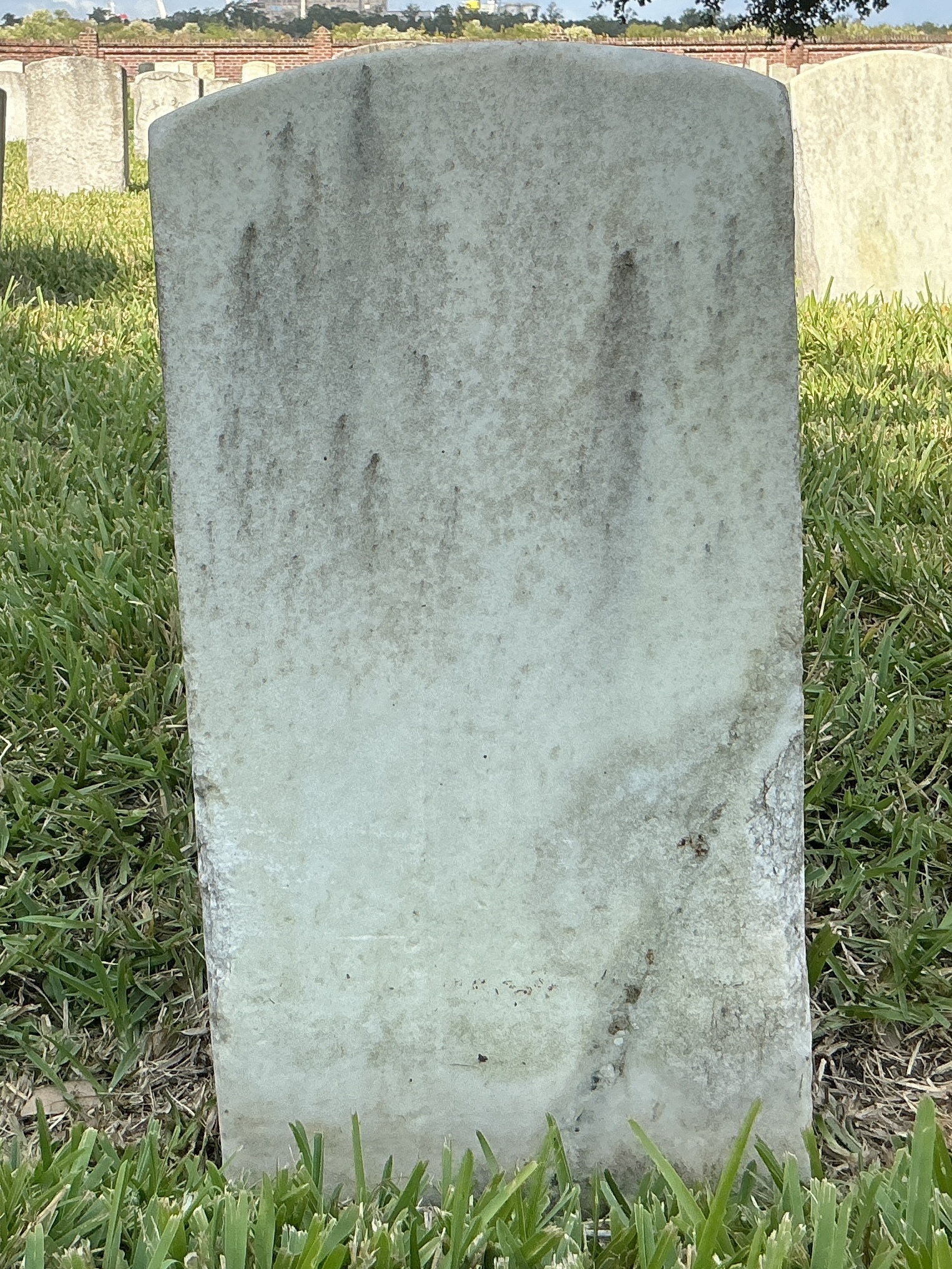 Back of historic upright marble headstone with recessed shield face.