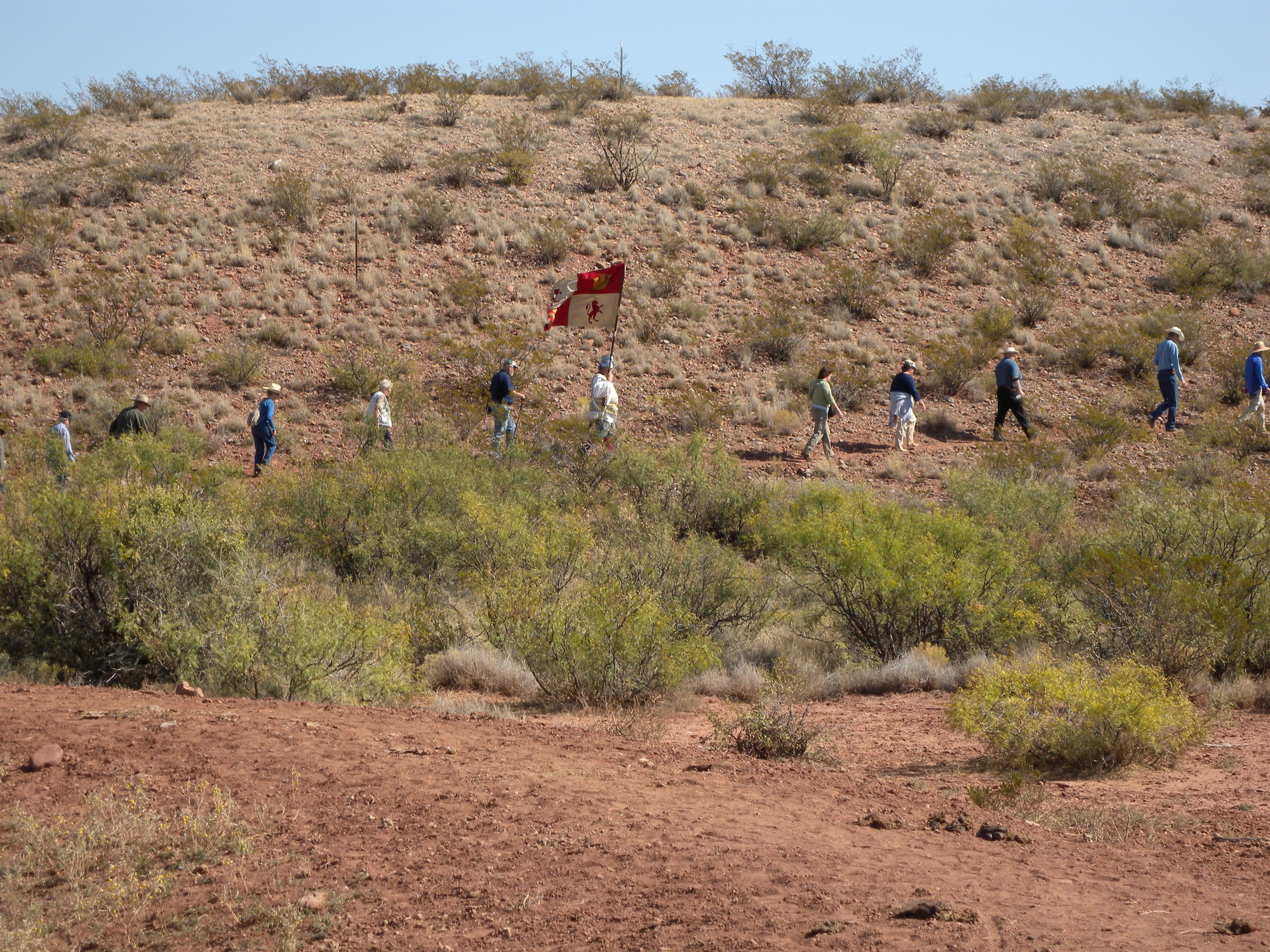 A group of people walking down a hill with a flag.