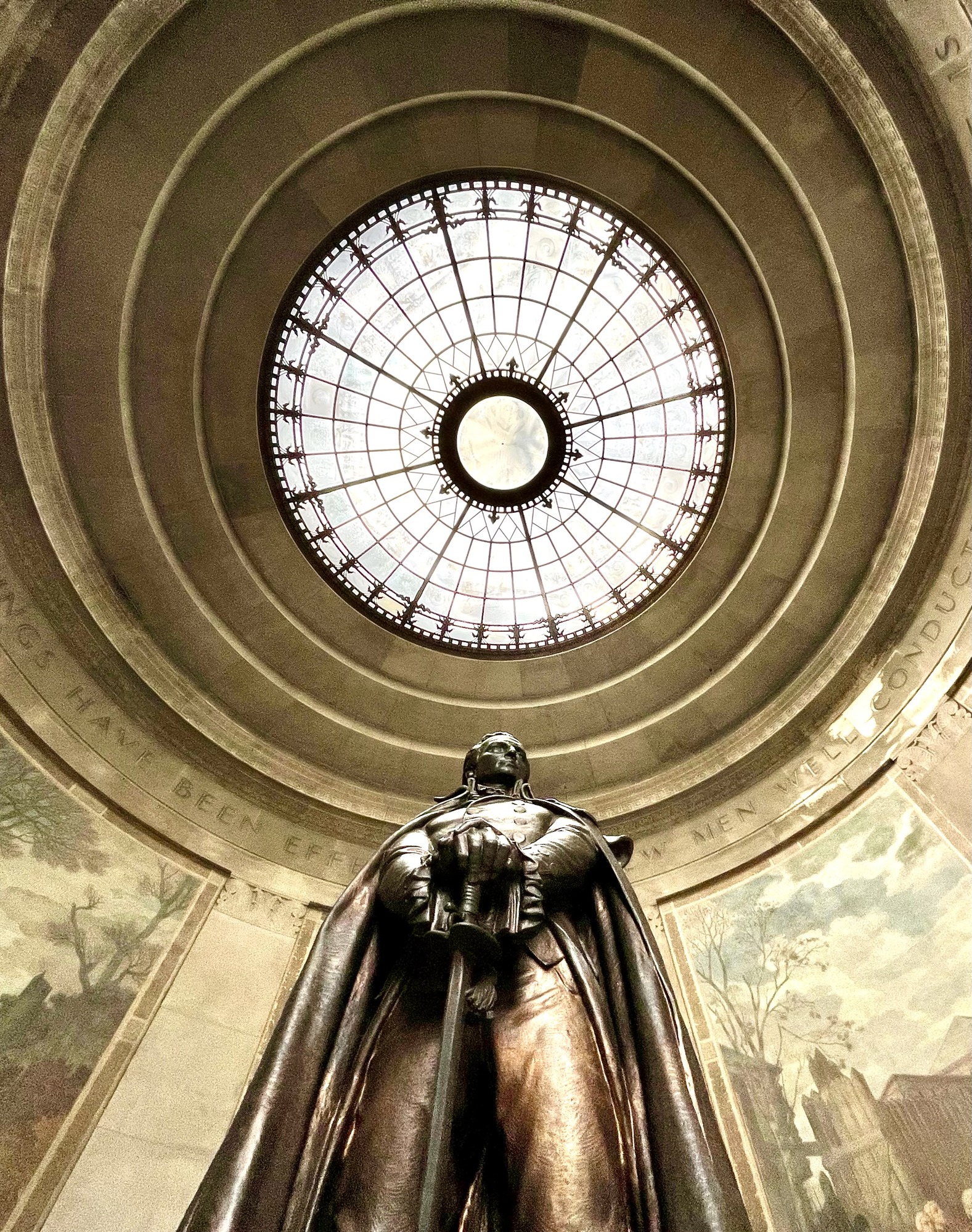Statue of George Rogers Clark in a memorial's rotunda decorated with paintings of historical events 