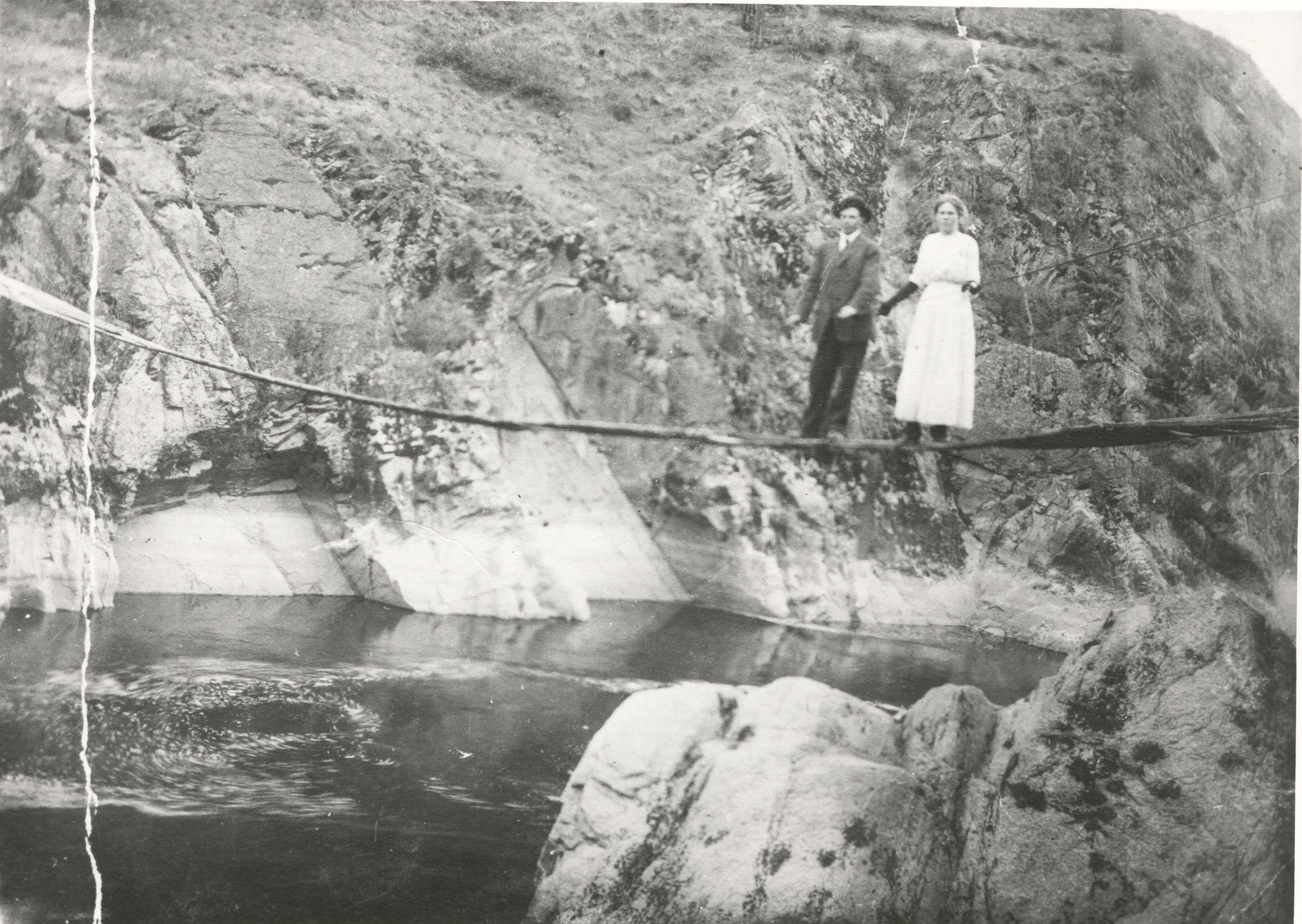 Black and white photograph of a man and a woman standing on bridge 