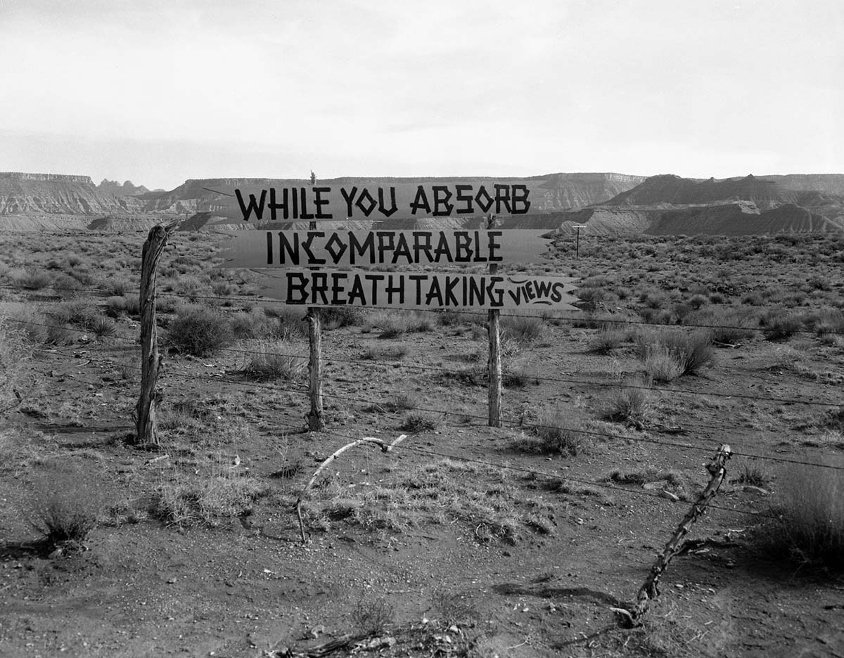 Grandma's signs on State Route 15 (now State Route 9), black on yellow at almost every turn from Virgin, Utah to Zion. Photo was taken to document the proposed cleanup project to remove undesirable signs and debris. This sign reads 'While you absorb incomparable breath taking views.' Rockville Mountain in the far distance.