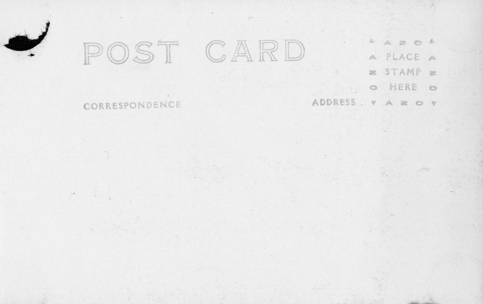The back of a postcard. The words "Post Card" are centered on the card, along with the subtitles "Correspondence" and "Address" under it. There is a box outlined with "AZO" and triangles on each corner, with the instructions "Place stamp here" at the center. There is no address, correspondence, or stamp.