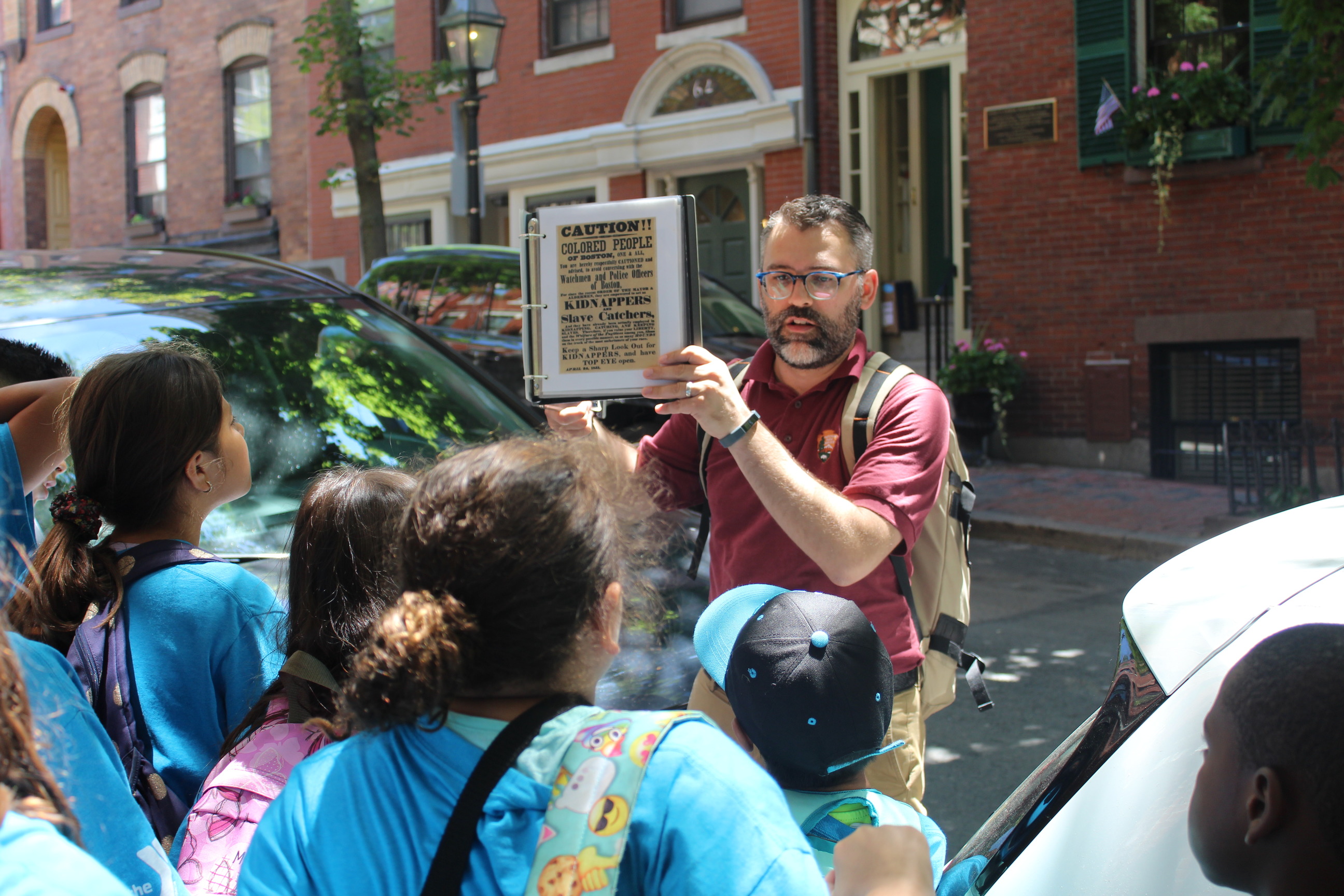 A bearded man holds up a copy of an 1850 leaflet