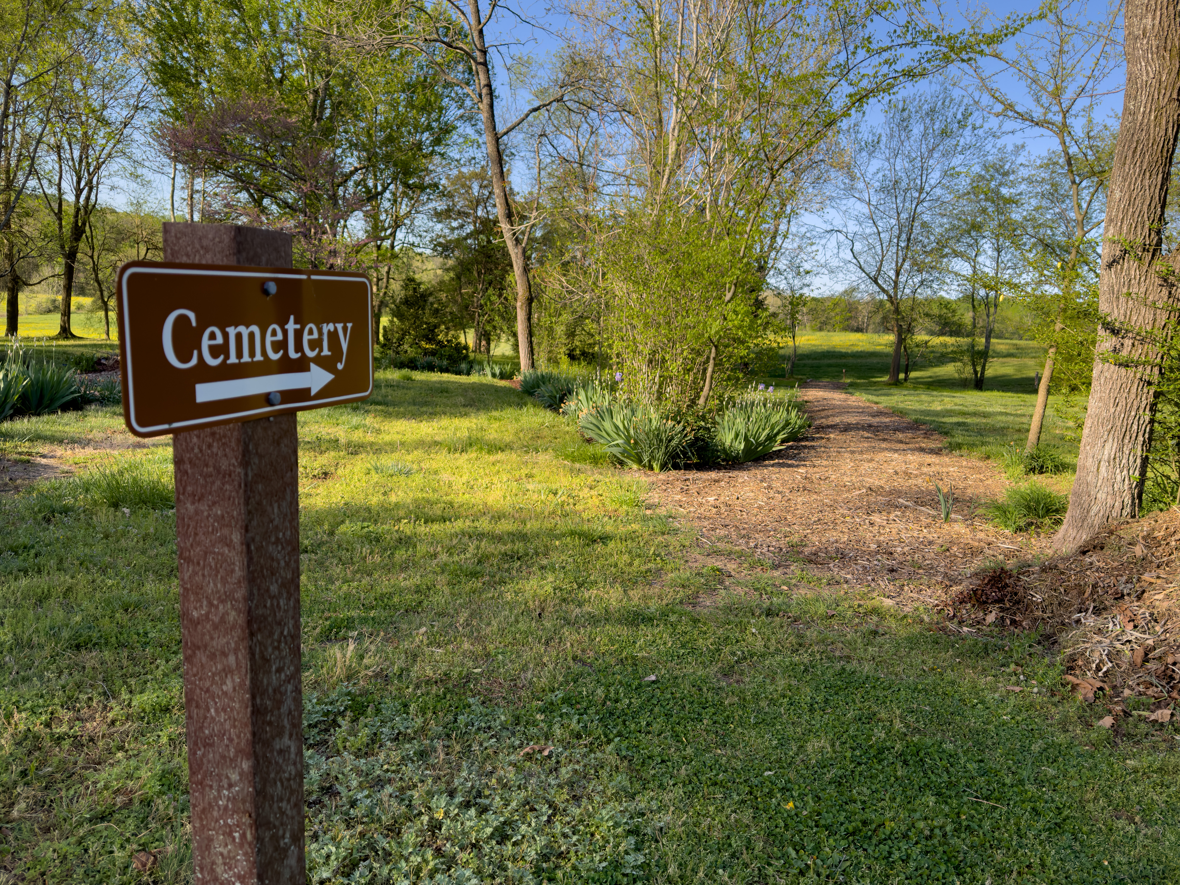 Brown sign leading to a path that reads cemetery.