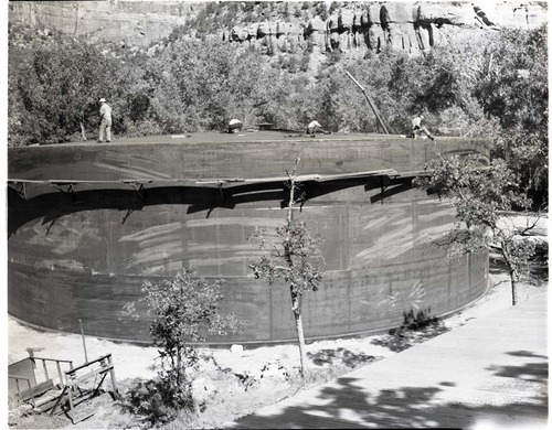 Construction of million gallon water tank at Birch Creek and Court of the Patriarchs. Top of tank in place, workers finishing cleaning and painting.