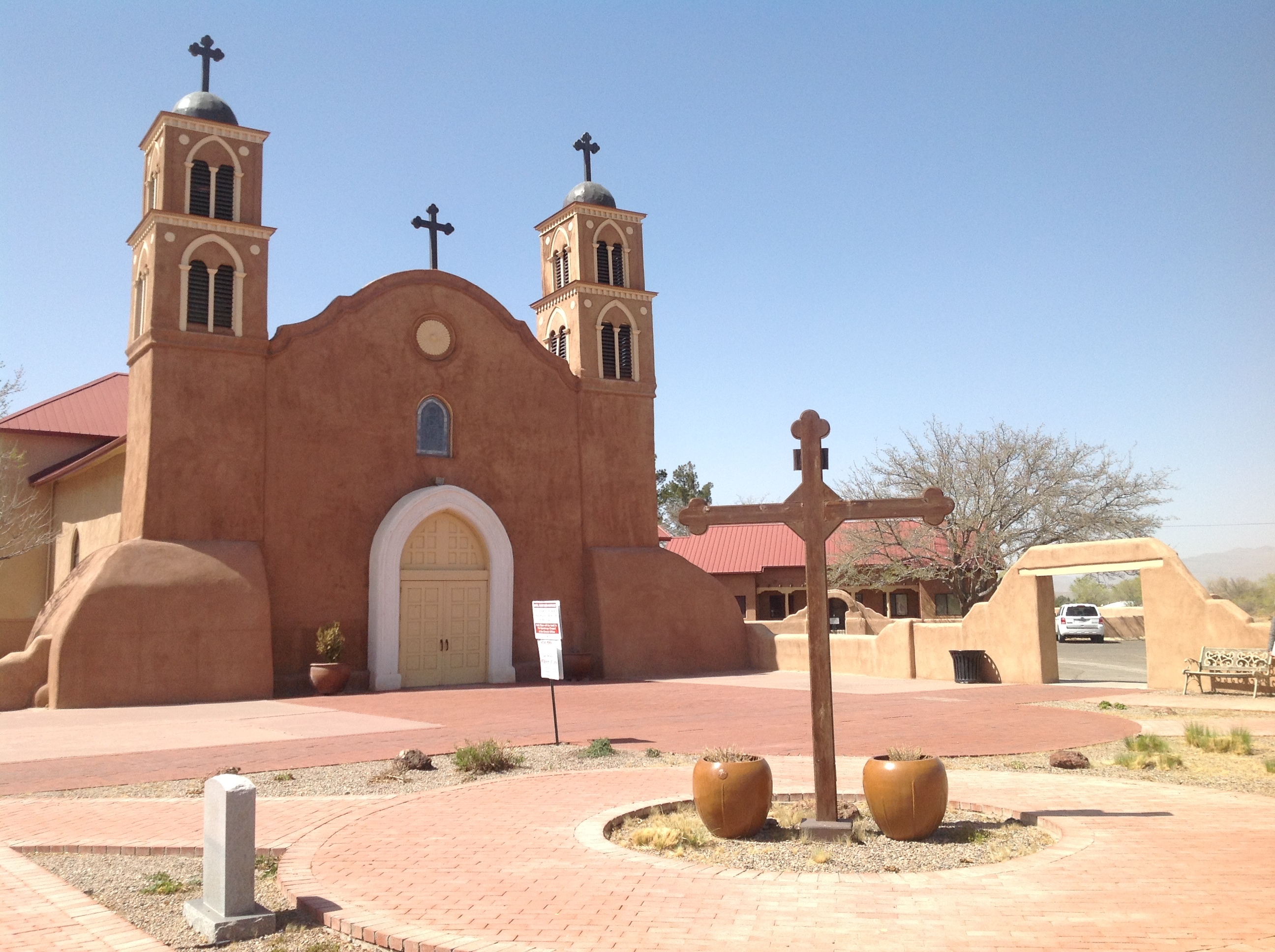 An adobe building with a cross in front of it.