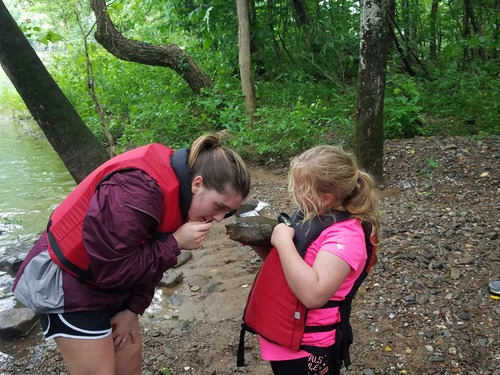 Girl Scout holding a magnifying glass up to a rock