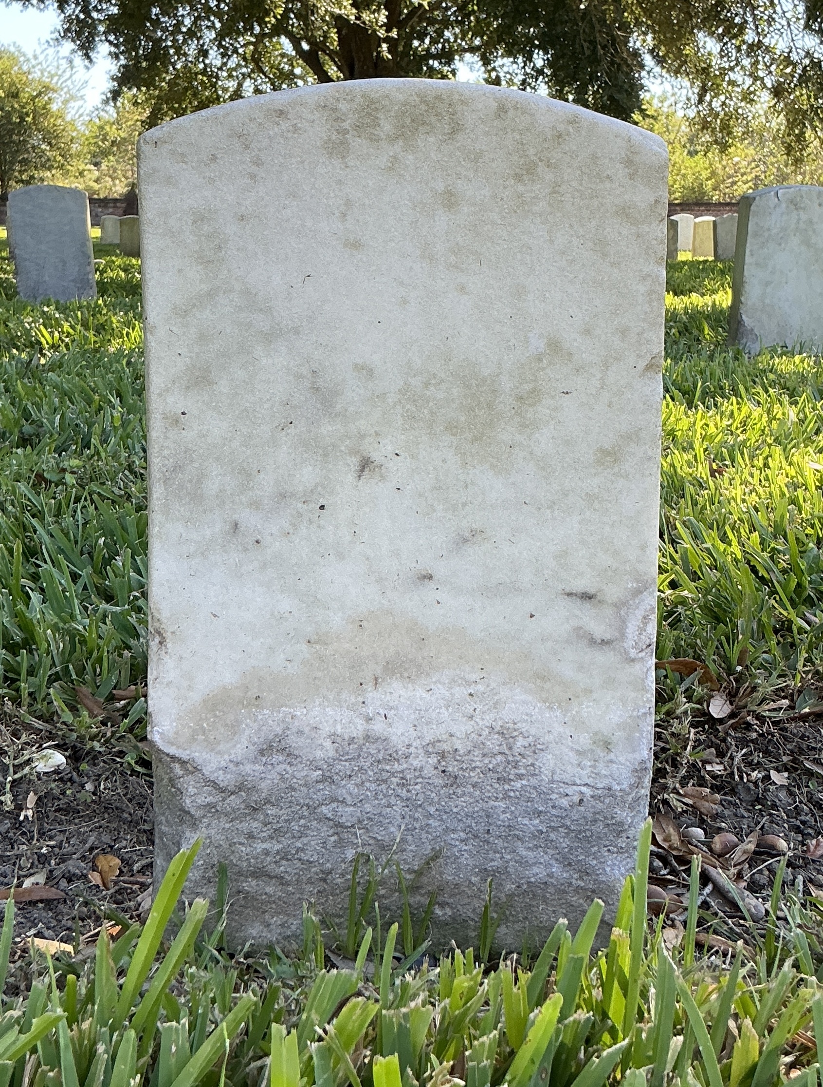 Back of historic upright marble headstone with recessed shield face.