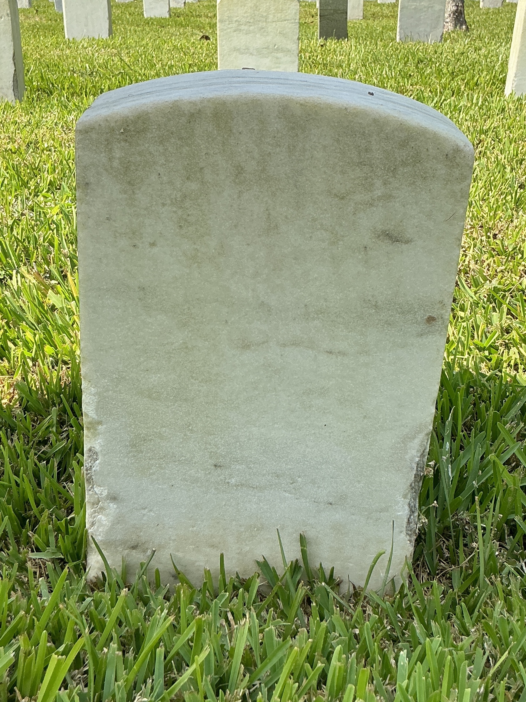 Back of historic upright marble headstone with recessed shield face.
