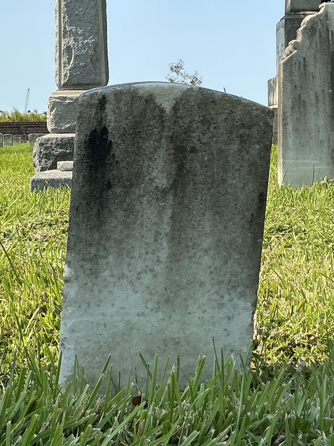 Back of historic upright marble headstone with recessed shield face.
