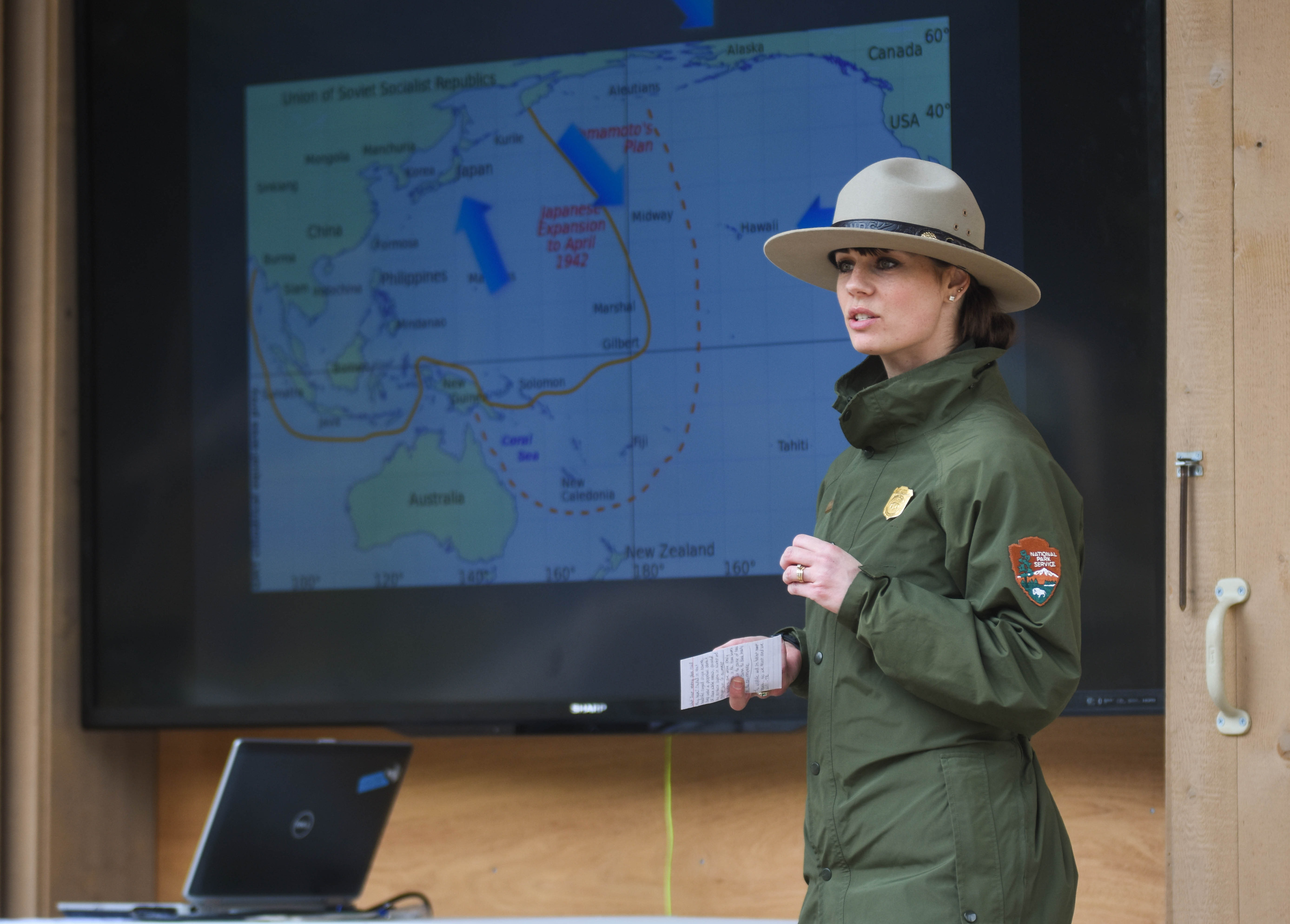 a park ranger standing in front of a screen projecting a map of the Pacific Ocean