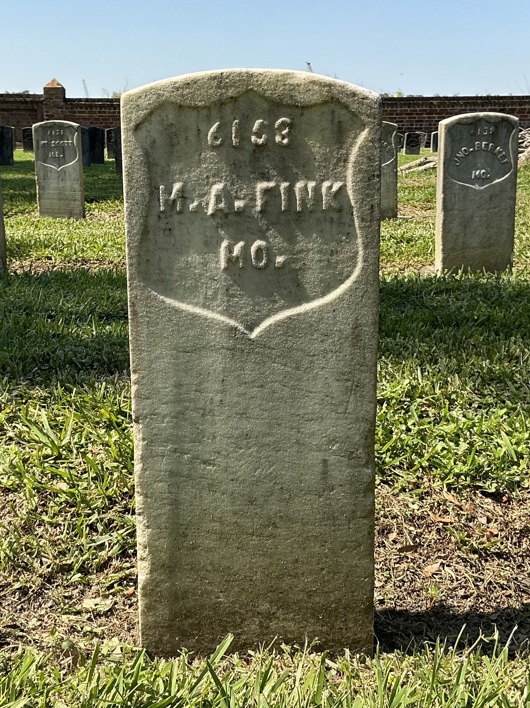 Front of historic upright marble headstone with recessed shield face.