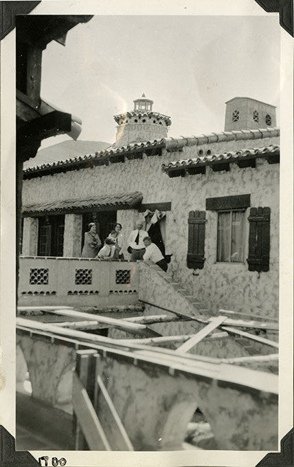 This is an historic black and white photograph from the Scotty's Castle Historic Photograph Collection, Death Valley National Park of group photograph of Helen Brown, Carrie Lee Johnson, Bessie Morris Penniman Johnson, Edna Devlin, Albert M. Johnson, and Walter Edward Perry Scott on Scotty's Castle Main House and Annex Bridge.  Circa 1928. Possibly photographed by Mat Roy Thompson.