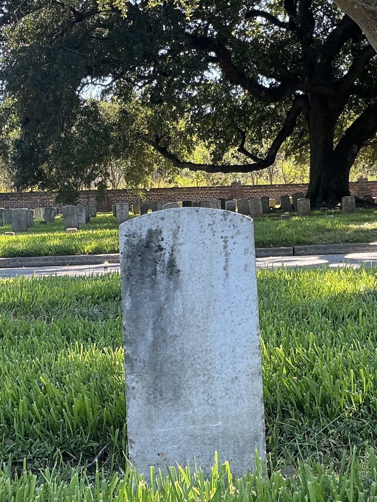 Back of historic upright marble headstone with recessed shield face.