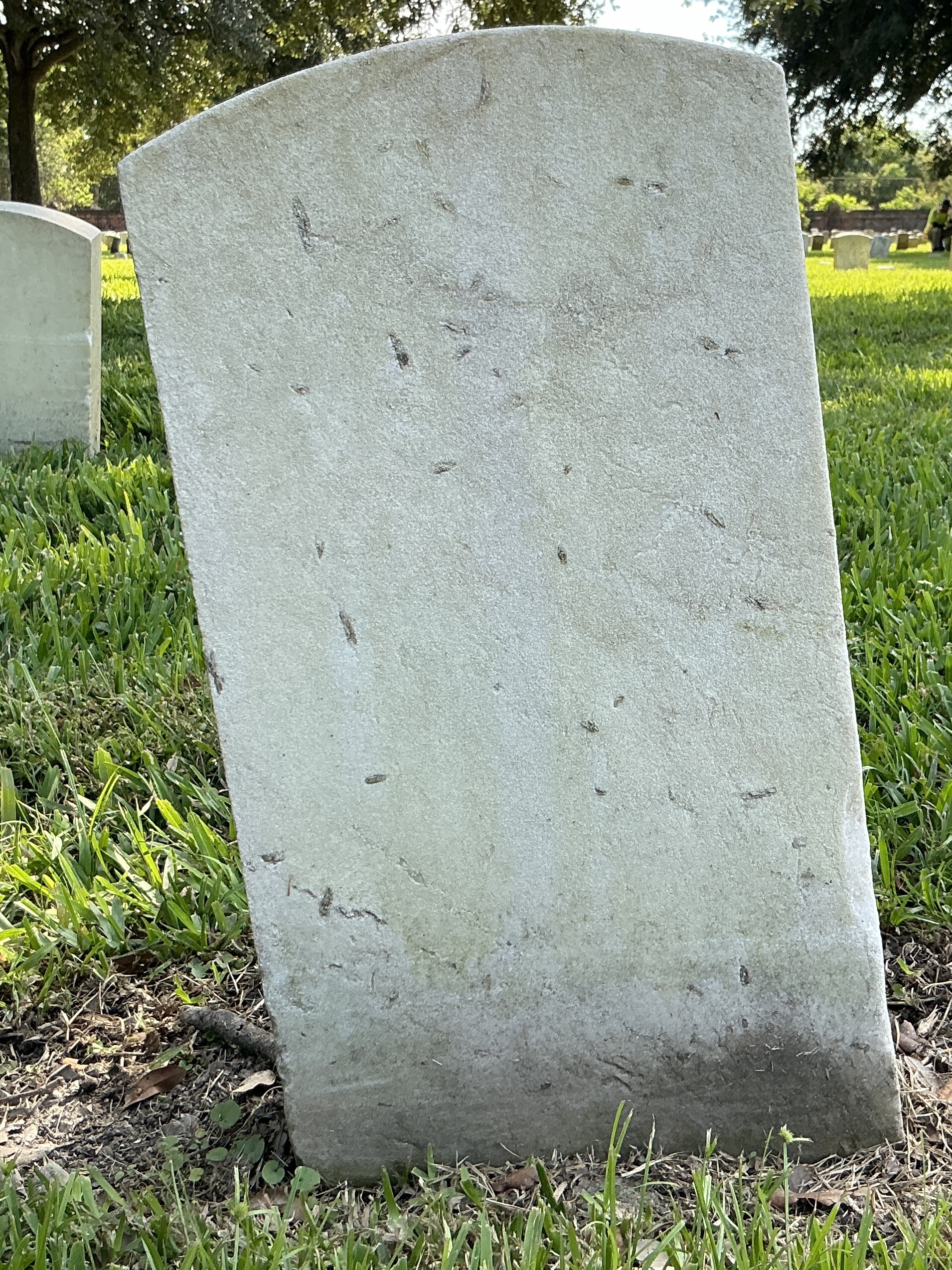 Back of historic upright marble headstone with recessed shield face.