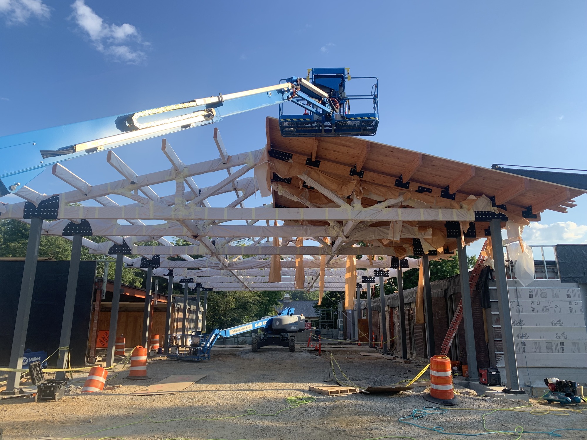 Construction project shows exposed beams and tresses of a large “a” shaped wooden roof.a