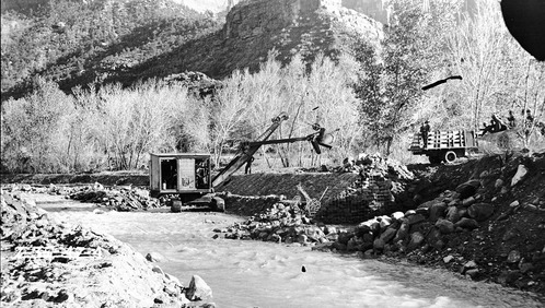 Channel change' rock cribbing channelization work alongside the Virgin River near the South Entrance. View of cc workers and steam shovel on river bank.