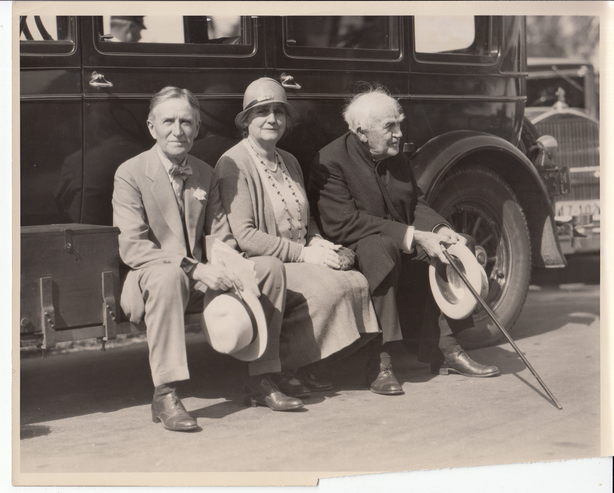 Harvey Firestone, Mina Edison, and Thomas Edison sitting on an automobile running board..