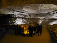 A large cave room with people standing around the center of the room. 