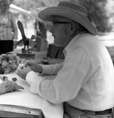 Bill Miller carving a peach pit creature at the first annual Folklife Festival, Zion National Park Nature Center, September 1977.