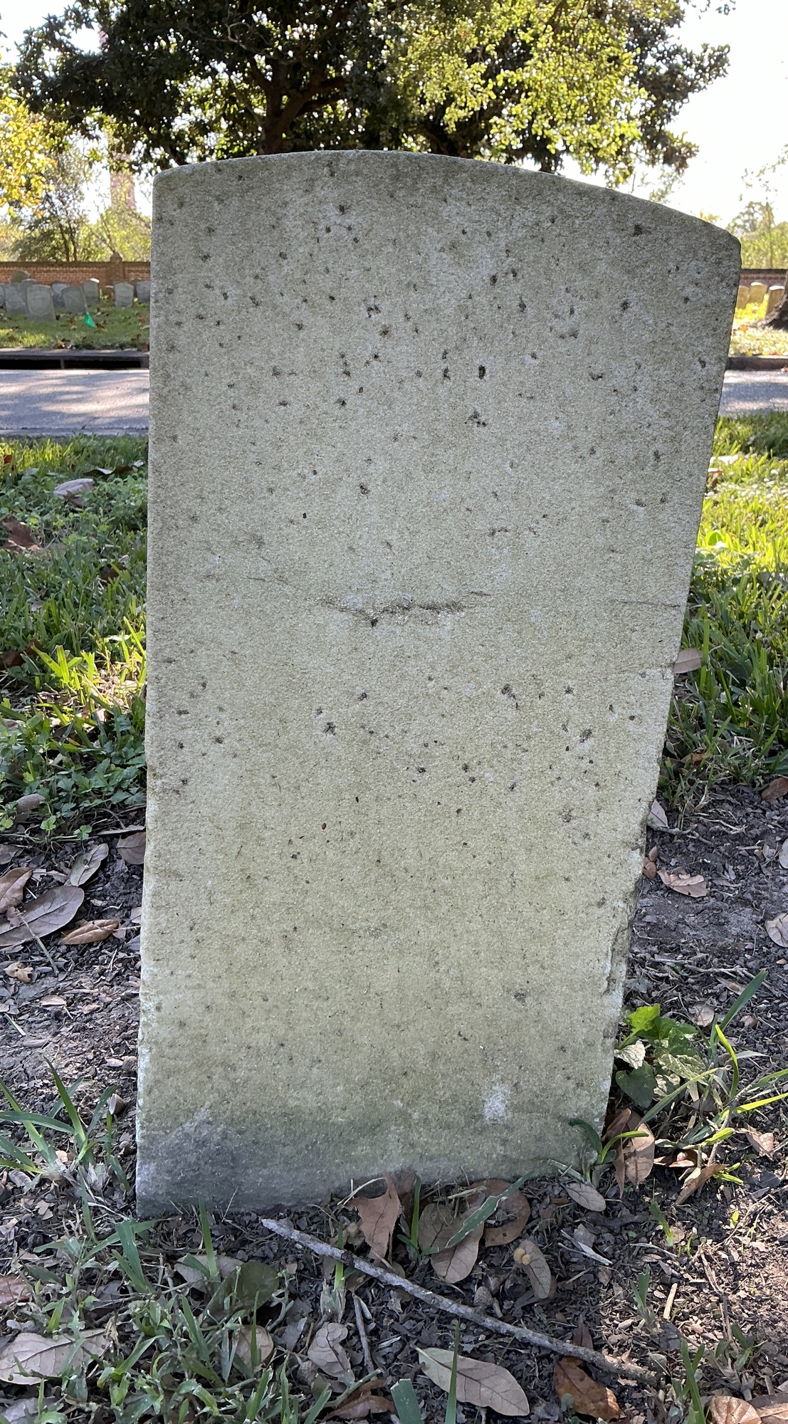 Back of historic upright marble headstone with recessed shield face.