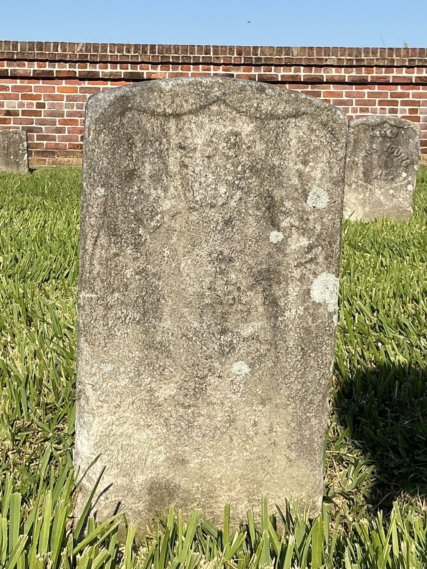 Front of historic upright marble headstone with recessed shield face.