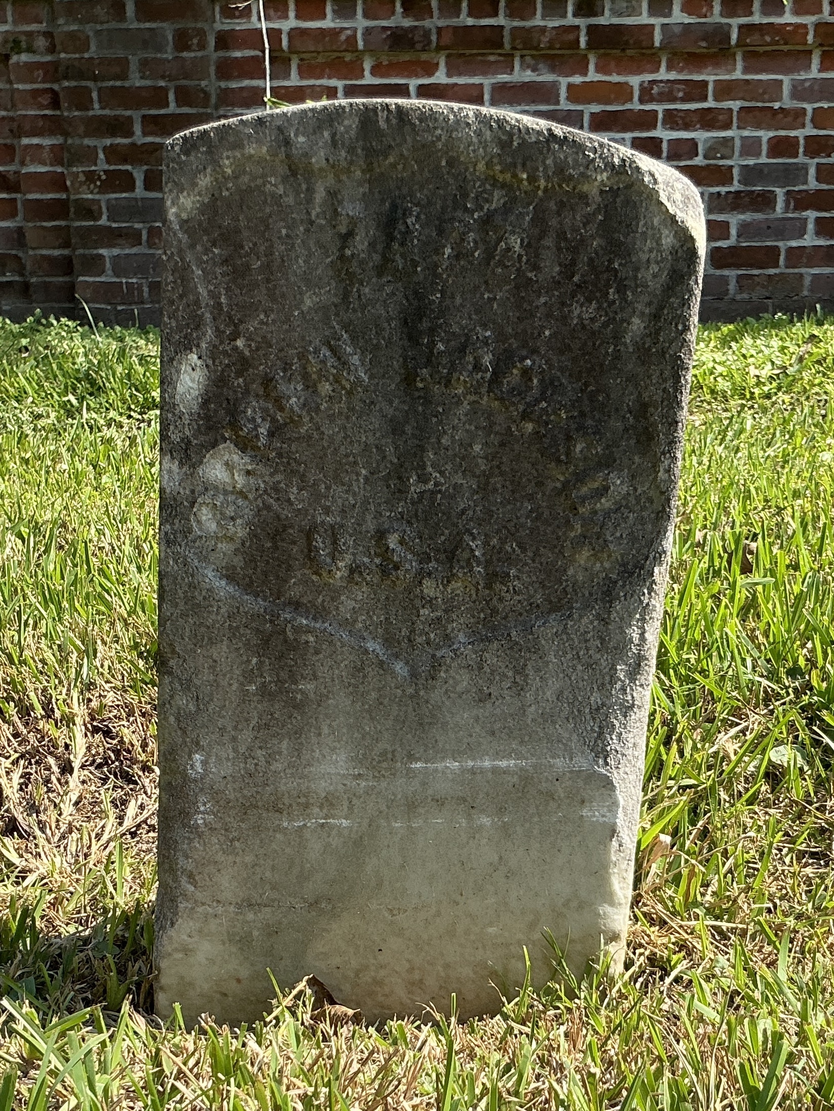 Front of historic upright marble headstone with recessed shield with recessed lettering face.