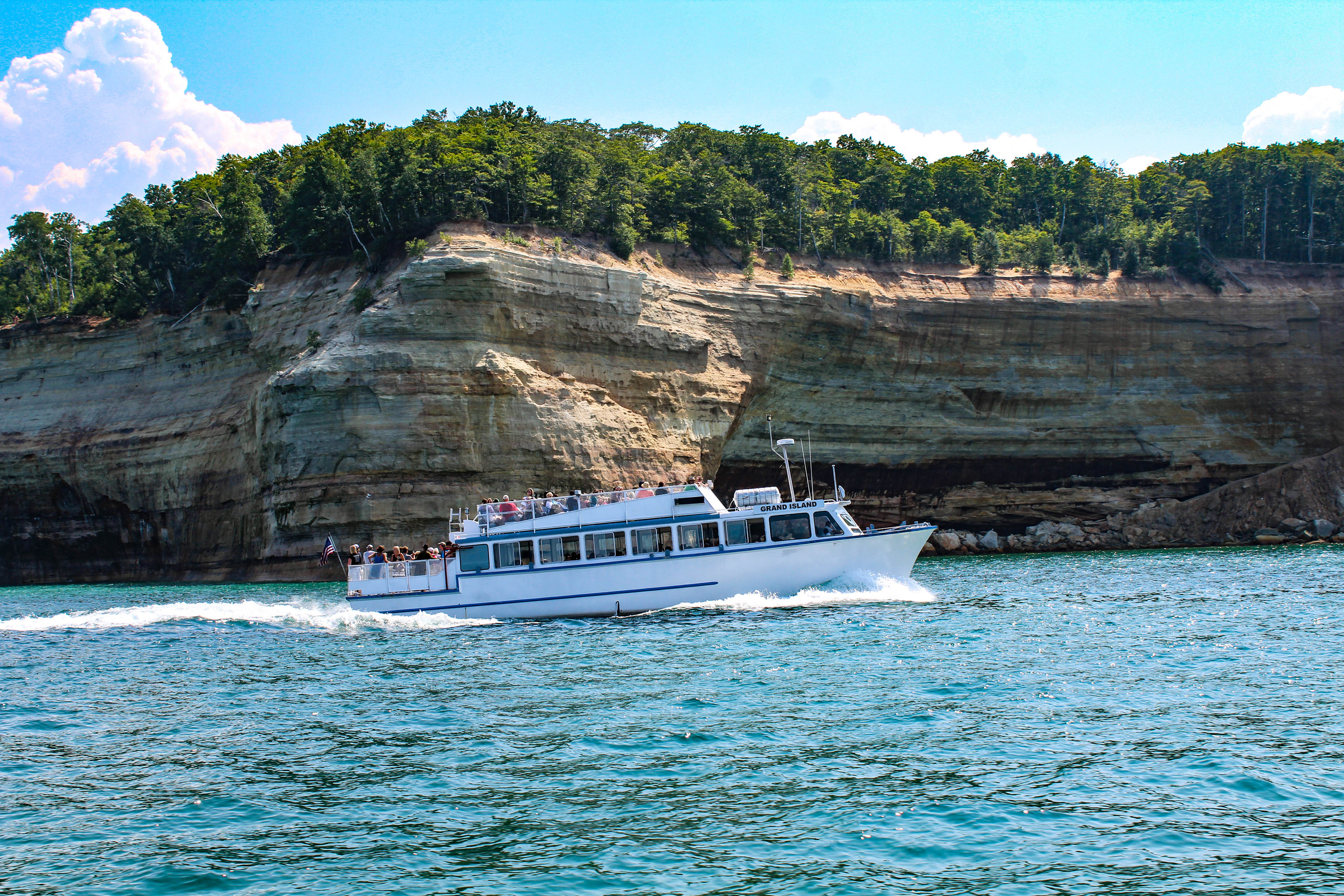 Passenger boat near a long cliff face in a lake